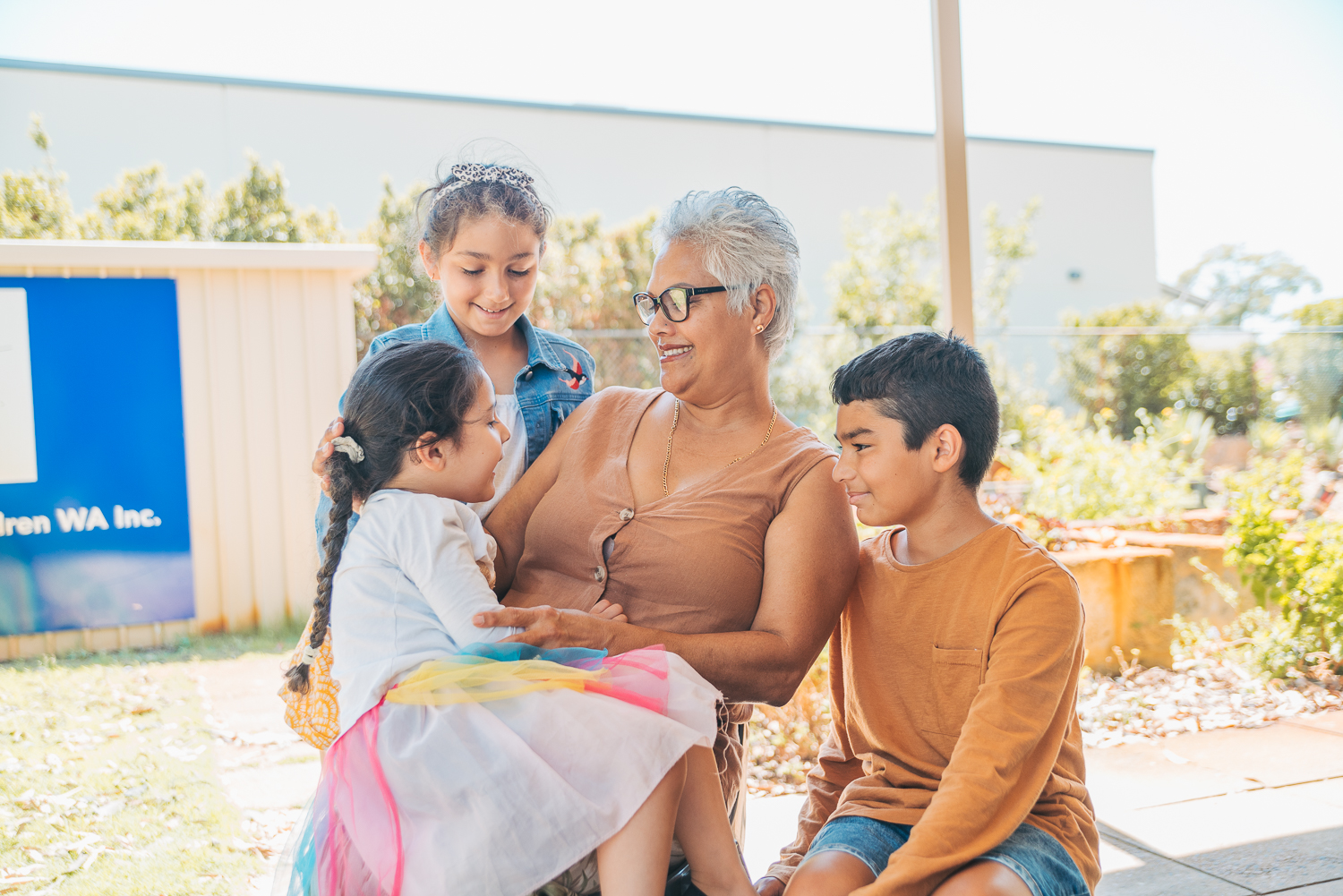 Grandmother with her three grandchildren smiling.