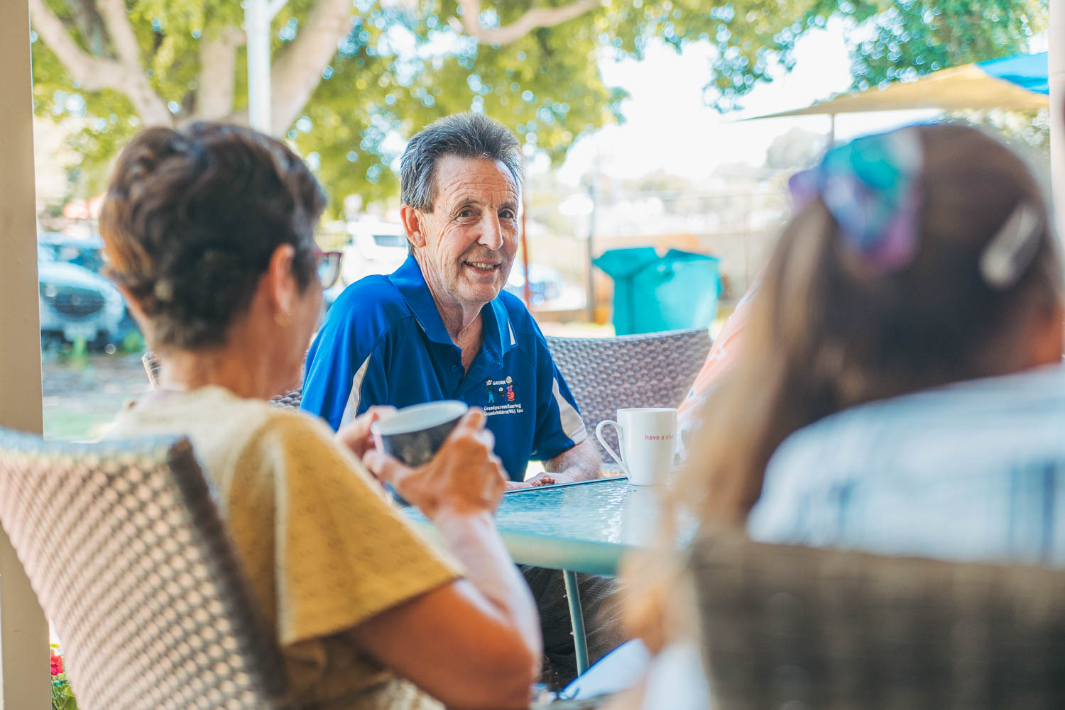 Grandfather at a table having coffee with other grandparents and grandchildren.